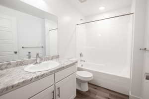 Full bathroom with wood finished floors, vanity, shower / washtub combination, and recessed lighting