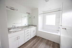 Bathroom with double vanity, bathing tub / shower combination, and wood finished floors