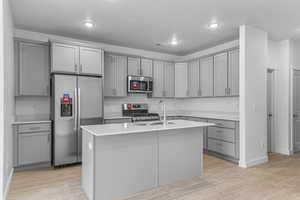 Kitchen featuring gray cabinetry, appliances with stainless steel finishes, light wood-style floors, light countertops, and recessed lighting