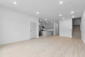 Unfurnished living room with light wood-type flooring, recessed lighting, and stairs