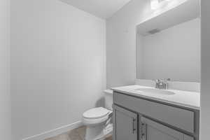 Half bathroom featuring vanity and toilet