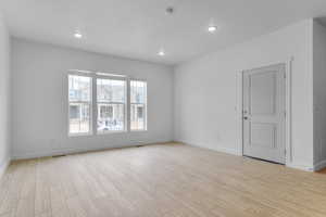 Empty room featuring light wood-type flooring and recessed lighting