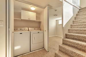 Laundry area featuring separate washer and dryer and light colored carpet