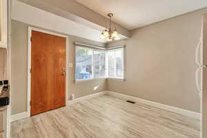 Unfurnished dining area featuring light wood-style floors and a chandelier