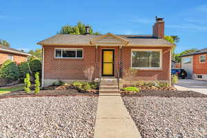 Bungalow-style home with a shingled roof, brick siding, and a chimney