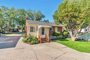 Bungalow-style house with entry steps, a chimney, a front lawn, roof with shingles, and brick siding