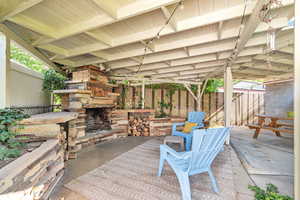 Fenced backyard featuring an outdoor stone fireplace and a patio area