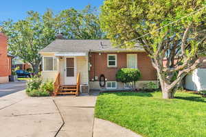 View of front of property with entry steps, a front yard, a shingled roof, and a chimney