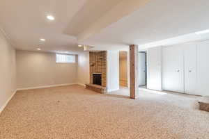 Basement with carpet, recessed lighting, and a brick fireplace