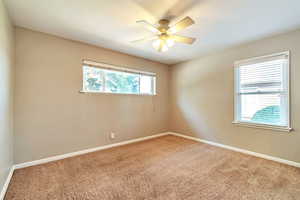 Carpeted spare room featuring baseboards and a ceiling fan