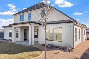Back of property with a patio area, stucco siding, and a lawn