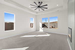 Unfurnished room with light carpet, plenty of natural light, a tray ceiling, recessed lighting, and ceiling fan