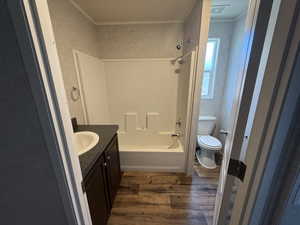 Bathroom featuring wood finished floors, vanity, washtub / shower combination, and ornamental molding