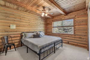 Bedroom with a wood ceiling with exposed beams, light colored carpet, log walls, and a ceiling fan