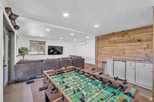 Recreation room with a textured ceiling, recessed lighting, wooden walls, and bar area