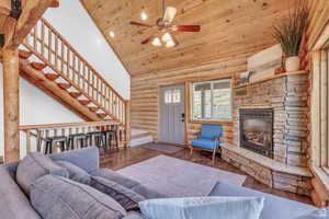 Living area with log walls, high vaulted ceiling, wood finished floors, a fireplace, and wooden ceiling