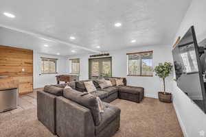 Living area featuring recessed lighting, a textured ceiling, french doors, light colored carpet, and light tile patterned floors