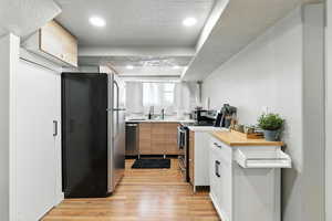 Kitchen featuring appliances with stainless steel finishes, light wood-type flooring, light countertops, recessed lighting, and white cabinets