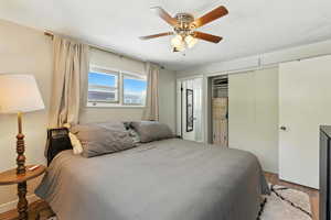 Bedroom featuring wood finished floors, a closet, a textured ceiling, and ceiling fan