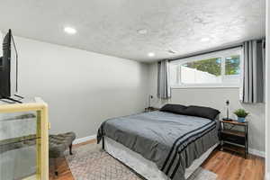 Bedroom with wood finished floors, a textured ceiling, and recessed lighting