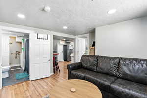 Living room with light wood-style floors, a textured ceiling, and recessed lighting