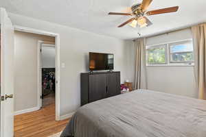 Bedroom with light wood-style flooring, a textured ceiling, and a ceiling fan