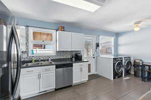 Kitchen featuring separate washer and dryer, fridge, dishwasher, backsplash, and a ceiling fan