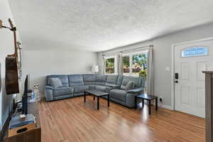 Living area featuring healthy amount of natural light, wood finished floors, and a textured ceiling
