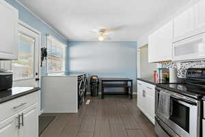 Kitchen with stainless steel range with electric stovetop, white microwave, backsplash, dark countertops, and a textured ceiling