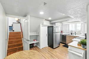 Kitchen with stainless steel appliances, modern cabinets, light countertops, light wood-style flooring, and recessed lighting
