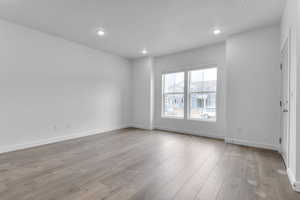 Unfurnished room with wood finished floors and recessed lighting