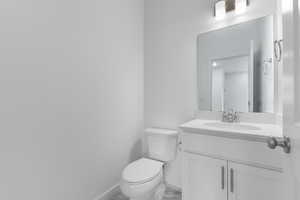 Half bathroom with marble look tile flooring and vanity
