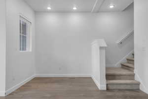 Stairs with wood finished floors and recessed lighting