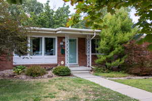 View of front of property featuring brick siding, a porch, and a front lawn