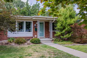 View of front of house with brick siding, covered porch, and a front lawn