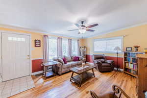 Living area featuring a ceiling fan, light wood-style floors, and ornamental molding