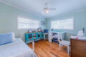 Bedroom with crown molding, light wood-style floors, and ceiling fan