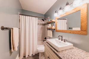 Full bathroom with vanity, shower / bath combo with shower curtain, and wood finished floors