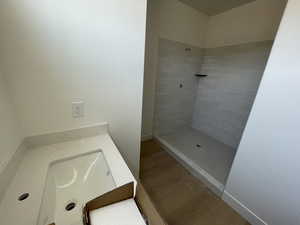 Bathroom featuring tiled shower and wood finished floors