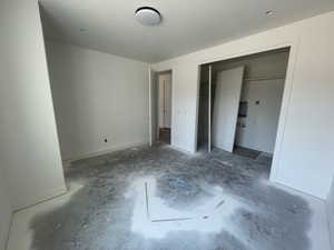 Unfurnished bedroom with unfinished concrete floors and a closet