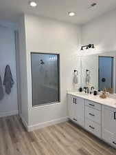 Bathroom with double vanity, wood finished floors, a shower, and recessed lighting