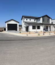 Modern inspired farmhouse featuring a standing seam roof, a garage, a metal roof, concrete driveway, and stucco siding