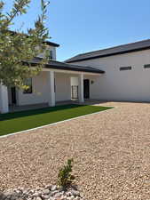 Rear view of house with stucco siding, fully landscaped backyard
