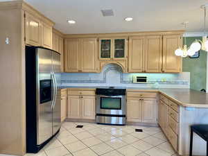 Kitchen with light brown cabinets, appliances with stainless steel finishes, light countertops, tasteful backsplash, and recessed lighting