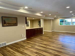 Family room with full attached kitchen, wood finished floors, recessed lighting, and a textured ceiling