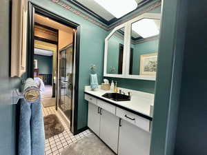 Full jack-and-jill style bathroom with vanity, tile patterned floors, and a stall shower