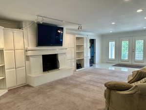 Family room conveniently located and adorned with, crown molding, a fireplace with raised hearth, rail lighting, and recessed lighting