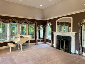 Elegant living room with carpet, a premium fireplace, recessed lighting, and ornamental molding surrounded by a wall of windows