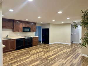 Kitchen with light countertops, black appliances, light wood-type flooring, and recessed lighting
