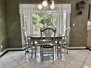 informal dining space featuring healthy amount of natural light, a chandelier, and light tile patterned flooring